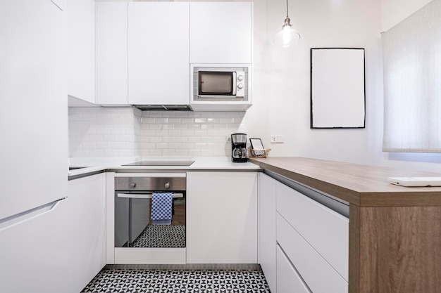 Cocina y mesa de cocina con muebles blancos y electrodomésticos de acero inoxidable con pisos de madera y baldosas hidráulicas