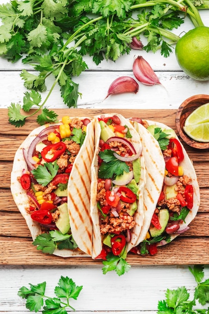 Cocina mexicana Tacos con carne de res, maíz, frijoles rojos, salsa de tomate y cebolla en tortilla de maíz a bordo Vista superior del fondo de la mesa blanca