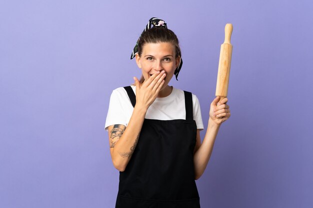 Cocina mujer eslovaca aislada en la pared púrpura feliz y sonriente cubriendo la boca con la mano