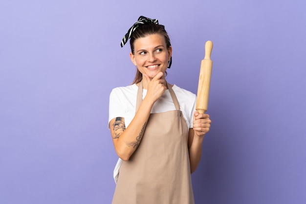 Cocina mujer eslovaca aislada en la pared púrpura mirando hacia el lado y sonriendo