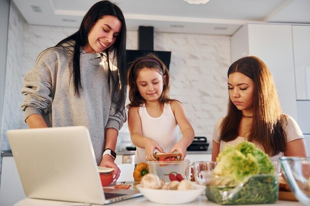 En la cocina Pareja lesbiana femenina con hija pequeña pasando tiempo juntos en casa