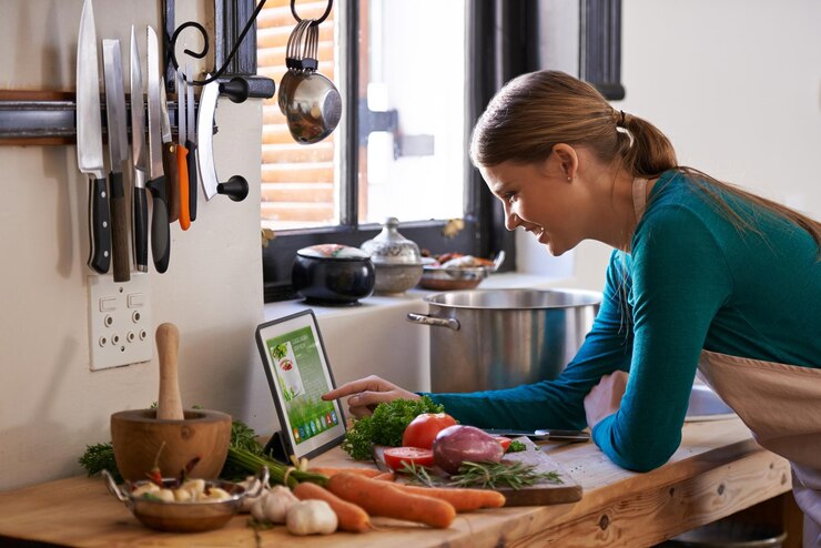 Foto cocina paso a paso captura de una mujer joven mirando una receta en línea en su tableta digital mientras prepara una comida