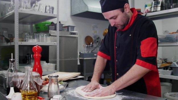 Cocina de restaurante un chef haciendo una masa para la pizza.