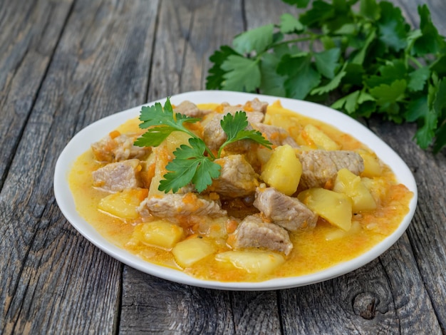 Cocina rumana carne casera fresca y patatas con perejil Estofado con carne de cerdo y verduras sobre un fondo de madera Almuerzo sabroso y nutritivo