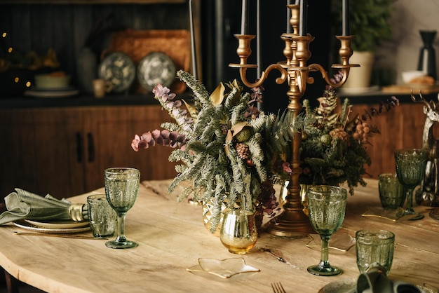 Cocina rústica que sirve mesa de madera y vasos vintage verdes con velas