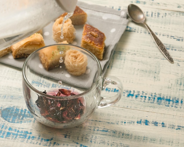 Cocina de té de frutas Verter agua hirviendo en una taza en el fondo de dulces orientales