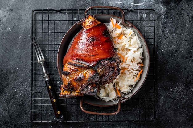 Cocina tradicional alemana Codillo de cerdo asado Schweinshaxe con chucrut Fondo negro Vista superior