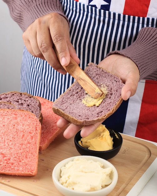 Cocina tradicional para el desayuno. Manos de mujer untando mantequilla sobre una rebanada de pan con un cuchillo sobre la mesa con una servilleta y pan de molde. De cerca. Concepto de pan o comer