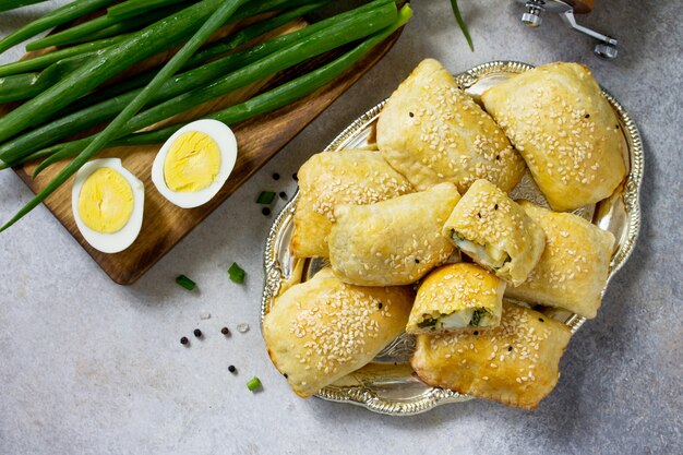 Cocina tradicional rusa Empanadas de huevo y cebollas verdes en la mesa de piedra clara Vista superior laicos plana