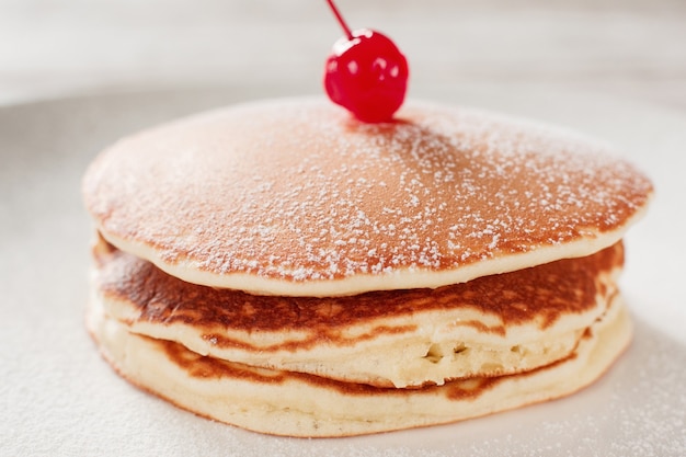 Foto cocinando comida. tortitas americanas con cereza sobre fondo de placa blanca. comida tradicional estadounidense.