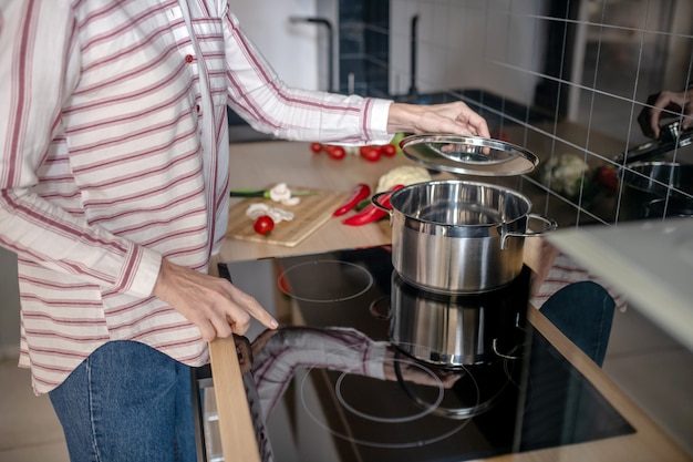 Cocinando. Mujer de pie cerca de la estufa en la cocina