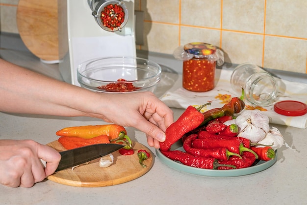 Cocinar adjika de pimiento picante y ajo molido en una picadora de carne preparaciones para el remedio popular de invierno para la gripe y los resfriados