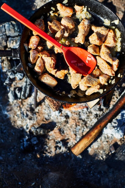 Cocinar al aire libre sobre una fogata con una cuchara roja