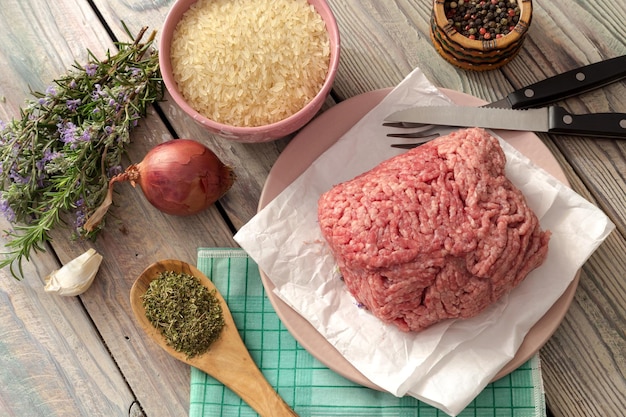 Cocinar alimentos Carne picada fresca cruda de arroz de res y verduras en un primer plano de fondo de madera