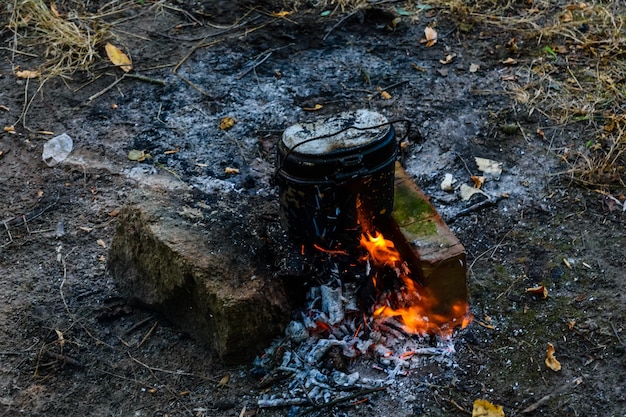Cocinar los alimentos en una tetera en la hoguera en el bosque