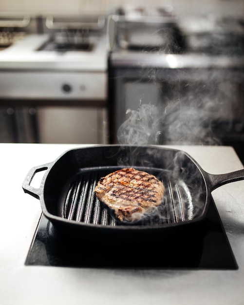 Cocinar bistec de ternera en una sartén a la parrilla en la cocina