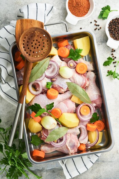 Cocinar caldo de pollo o asado en una sartén o olla con verduras patatas zanahorias y hierbas en la cocina encimera de hormigón gris paisaje desde arriba Cocinar preparar caldo de pollo Maqueta