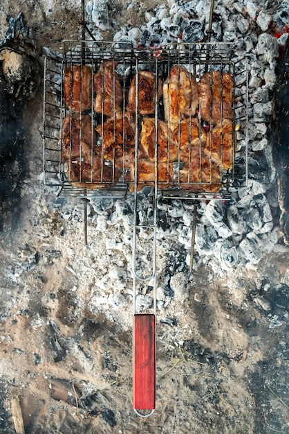 Foto cocinar carne de cerdo en una parrilla en el bosque con carbón