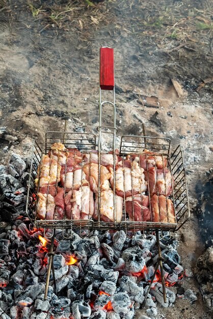 Foto cocinar carne de cerdo en una parrilla en el bosque con carbón