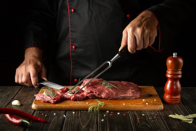 Cocinar carne de res cruda a manos de un chef en una tabla de cortar de cocina Idea para un menú de hotel