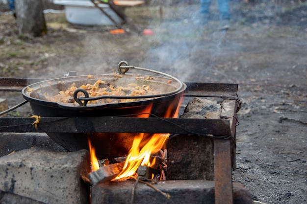 Cocinar carne con verduras en un caldero grande, comida callejera al aire libre.