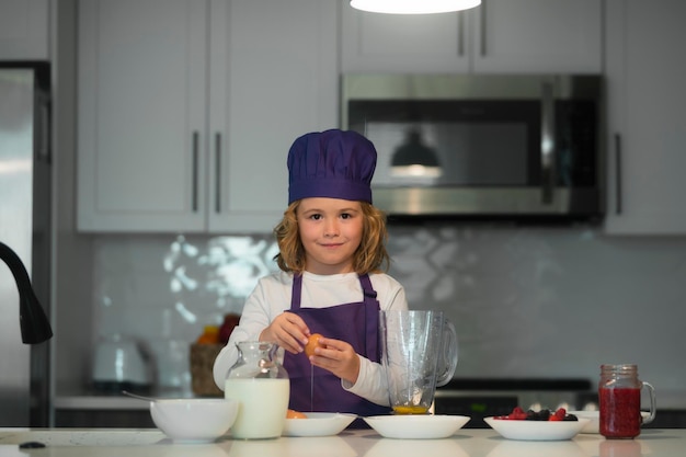 Cocinar en la cocina niño con sombrero de chef y delantal preparándose en la cocina