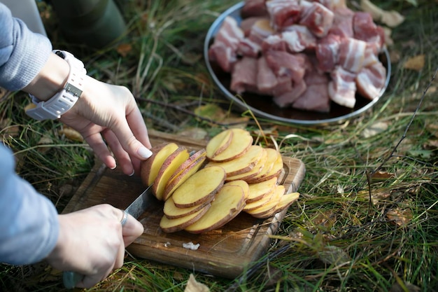 Cocinar comida en la naturaleza Manos cortando papas para barbacoa Picnic