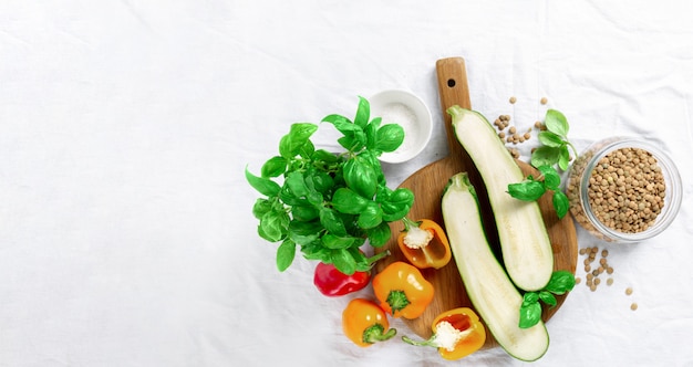 Cocinar concepto de comida saludable Calabacín, pimientos, albahaca y lentejas sobre fondo blanco vista superior