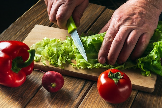 Cocinar la ensalada en la cocina del restaurante Chef manos cortan ensalada de verduras Conjunto de verduras para la dieta de la ensalada