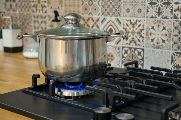 Foto cocinar en una estufa de gas. la olla en el quemador de gas. concepto de cocina casera.