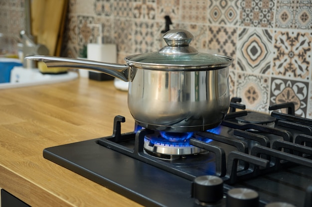 Foto cocinar en una estufa de gas. la olla en el quemador de gas. concepto de cocina casera.