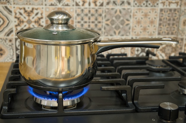 Cocinar en una estufa de gas. La olla en el quemador de gas. Concepto de cocina casera.