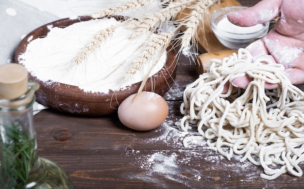 Cocinar fideos en casa. Las manos sostienen los fideos crudos.