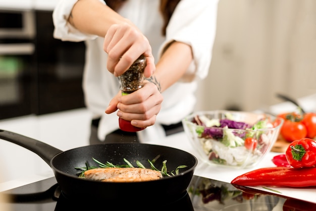 Cocinar el filete de pescado con las verduras y las especias en una cacerola en la cocina. Alimentación sana y nutrición.