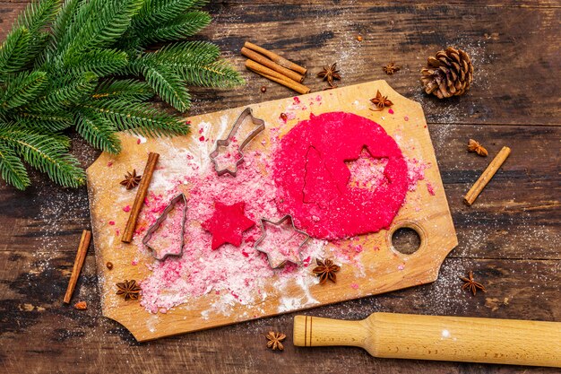 Cocinar galletas de jengibre rojo. Pasteles tradicionales de Navidad. Abeto, especias, cortadores de galletas, masa cruda, rodillo, tablas de madera