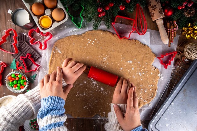 Cocinar galletas de Navidad antecedentes familiares Madre e hija manos vista superior en un acogedor fondo de madera haciendo galletas de pan de jengibre con cortadores de galletas con decoración de Navidad de Año Nuevo