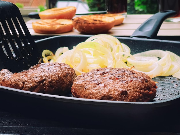 Cocinar hamburguesa de ternera picada en una sartén de parrilla de hierro fundido al aire libre carne roja en una sartén asar comida en el jardín Vivir en la campiña inglesa