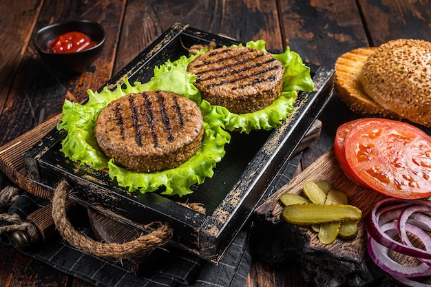 Cocinar hamburguesas sin carne a base de plantas con chuletas asadas sin carne vegetariana empanadas de tomate y cebolla en una bandeja de madera Fondo de madera Vista superior