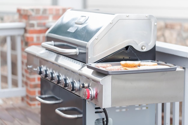 Cocinar hamburguesas clásicas en una parrilla de gas al aire libre en verano.