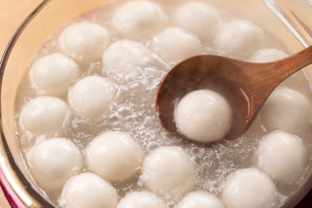 Cocinar y hervir las tradicionales bolas de bola de masa de arroz y tangyuan, tang yuan para el solsticio de invierno y la comida del festival yuanxiao.