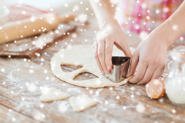 cocinar, hornear, personas y concepto de hogar - cerrar las manos de las mujeres haciendo galletas con masa fresca en casa