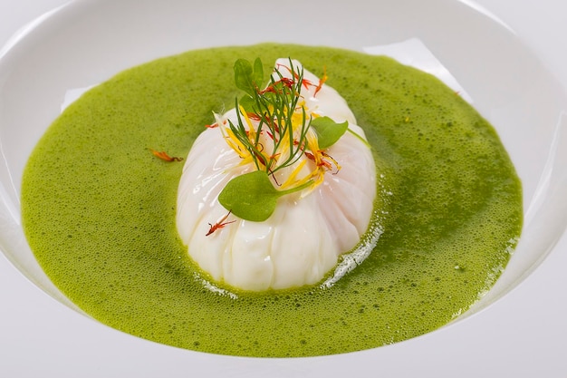 Cocinar con ingredientes locales huevo escalfado y sopa saludable verde de cerca en un plato blanco