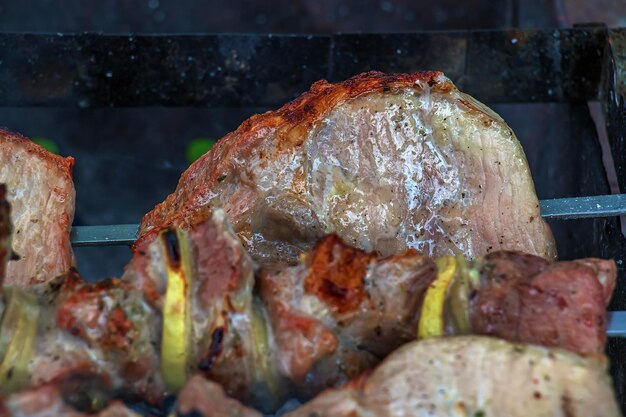 Cocinar kebabs en una parrilla con humo Carne de barbacoa marrón fresca cocinada en una parradera al aire libre