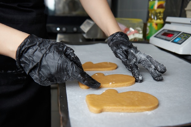 Cocinar con las manos enguantadas hace galletas usando un molde de masa