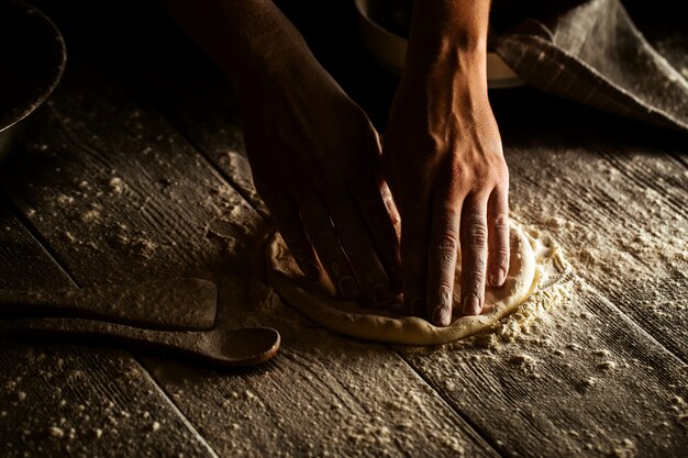 Cocinar las manos de la panadería desmorona la masa en un pastel plano