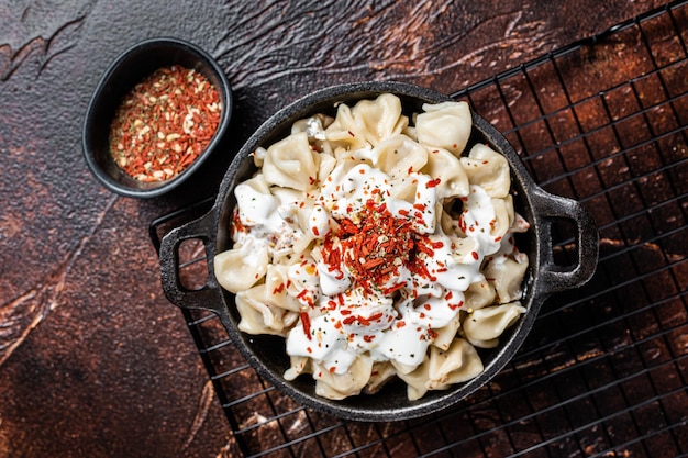 Cocinar Manti Dumpling con yogur y salsa de tomate en una sartén Fondo oscuro Vista superior