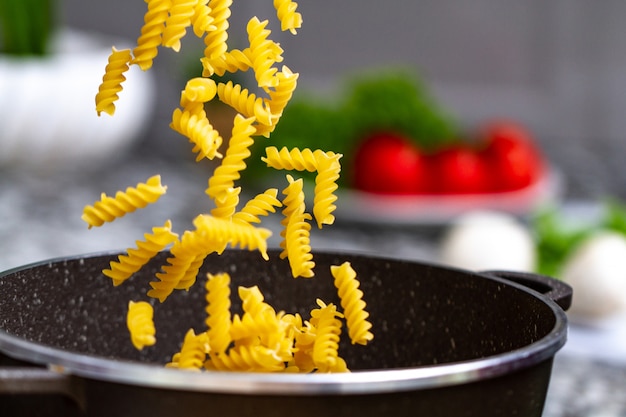 Cocinar pasta en casa para almorzar. Verter fusilli en una cacerola