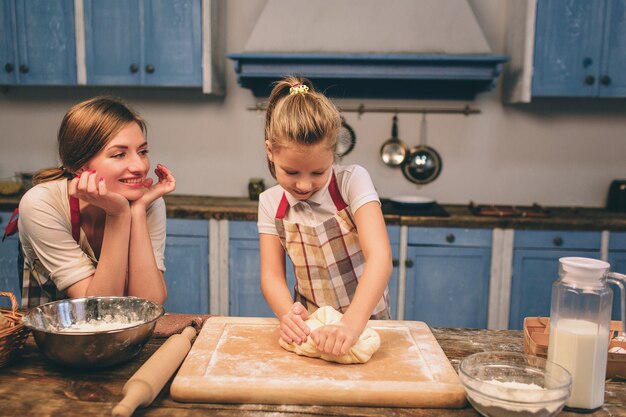 Cocinar pasteles caseros. Feliz familia amorosa están preparando panadería juntos. Madre e hija hija están cocinando galletas y divirtiéndose en la cocina. Envuelve la masa.