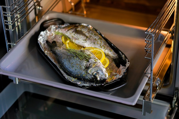 Cocinar pescado con cereza limón y hierbas sobre pergamino en el horno