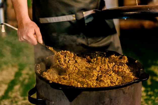 Cocinar pilaf en la calle, foto de noche con ruido